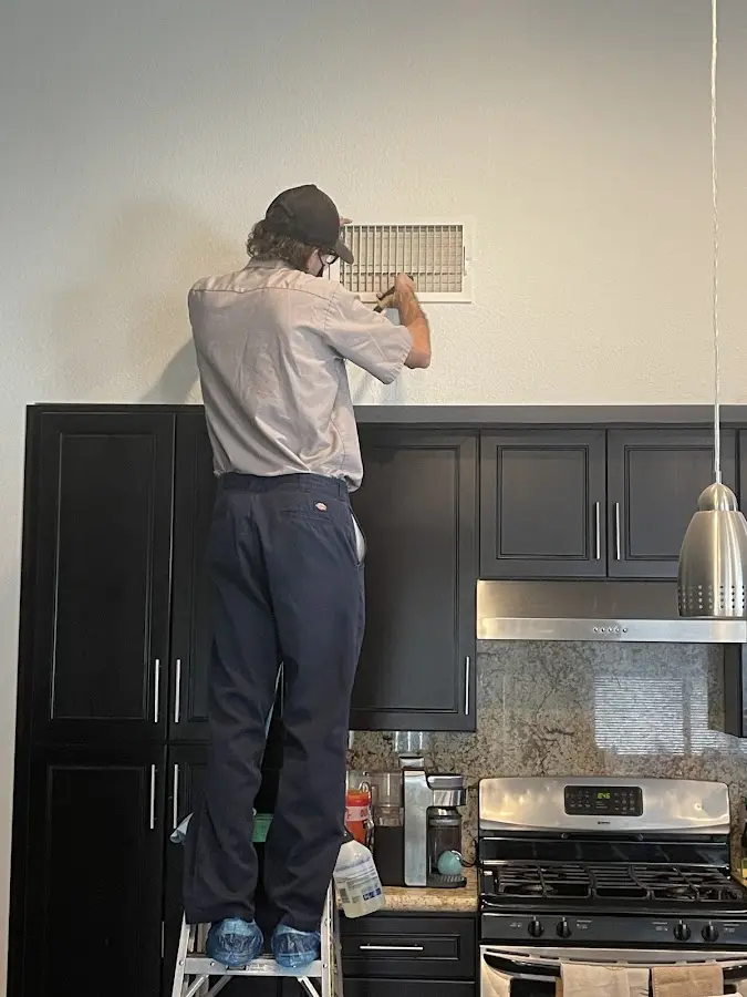 Technician inspecting an air vent during HVAC service in Sierra Madre